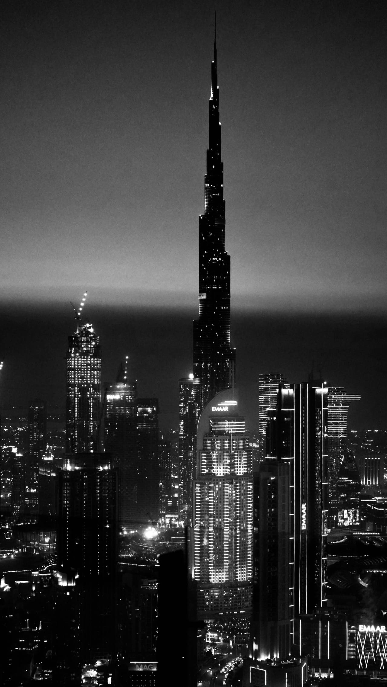 Downtown Dubai at night in black and white, tower windows lit against an empty sky