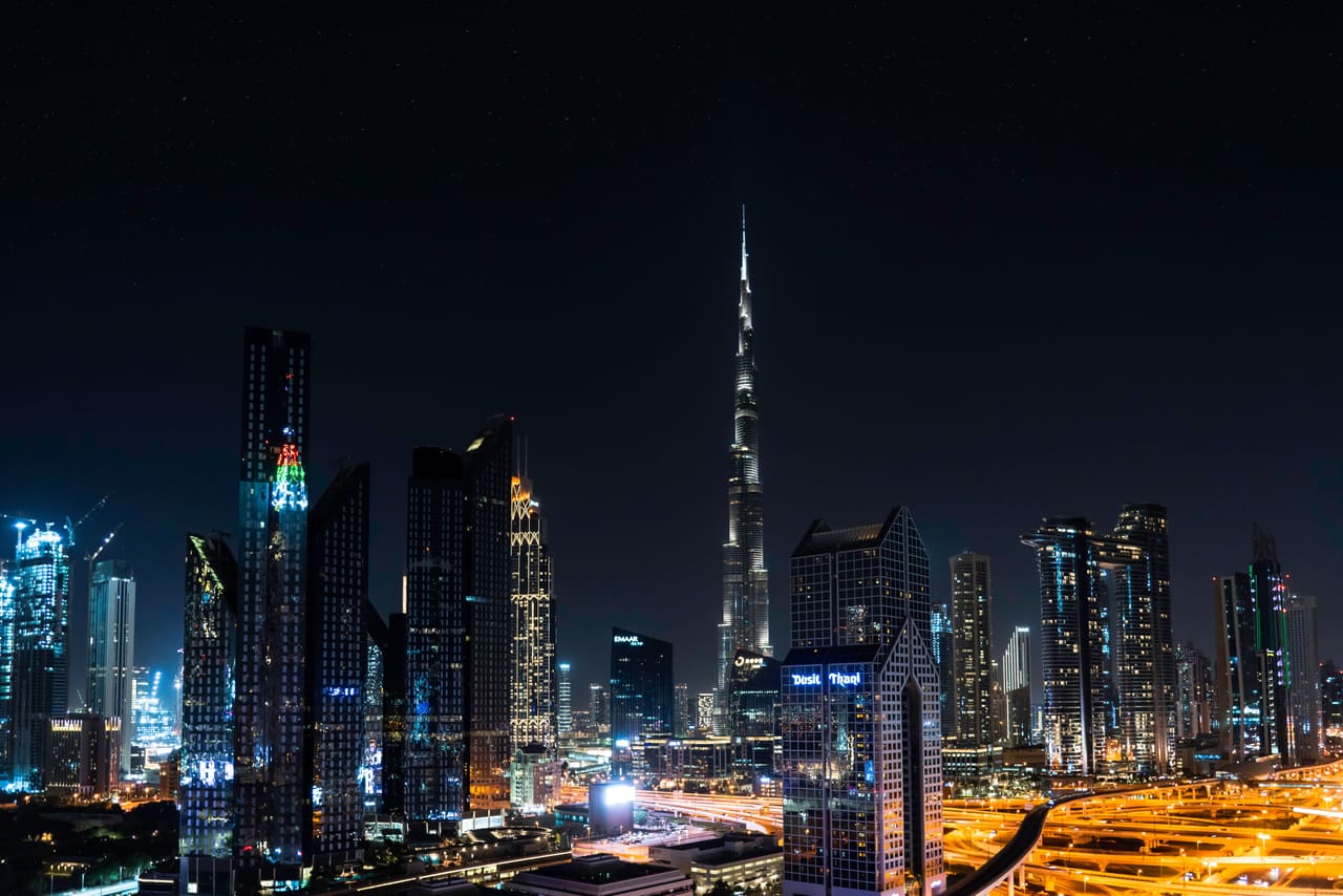 The Downtown Dubai skyline after dark, the Burj Khalifa rising above the surrounding towers