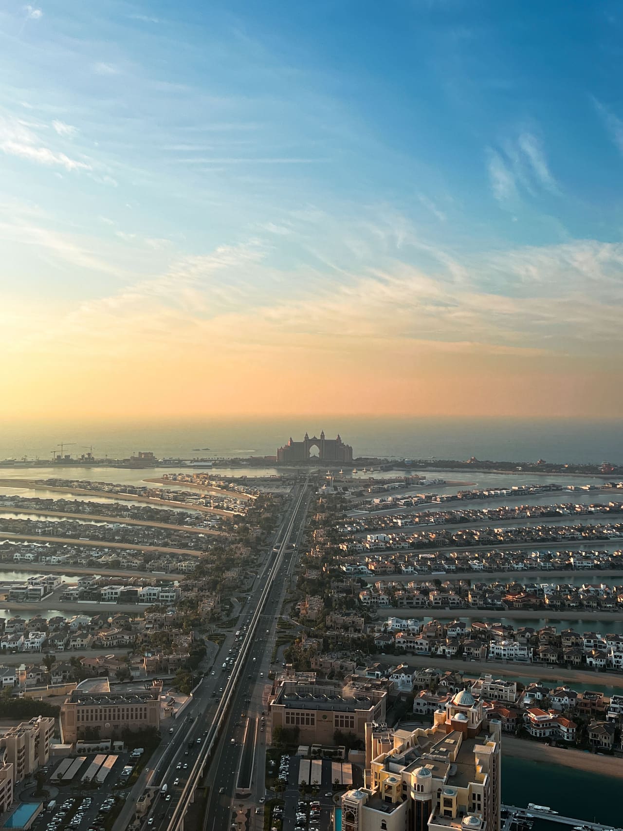 Palm Jumeirah from the air at dusk, the fronds of villas lit against the sea